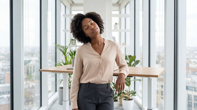 Business professional woman doing neck stretching exercise at bright office desk for workplace wellness and mental health stress relief