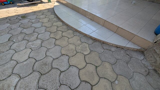 Outdoor paved walkway with hexagonal concrete pavers and tiled steps in urban courtyard