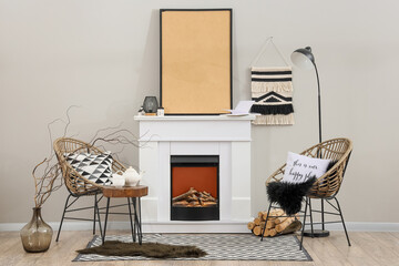Obraz premium Cozy living room interior with modern fireplace, wicker chairs, and blank picture frame for home decor
