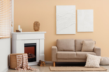 Obraz premium Cozy living room interior with beige sofa, white fireplace, and modern wall art decor