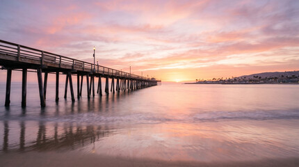 Obraz premium Sunrise over Newport Beach Pier with pink sky and ocean reflection in California