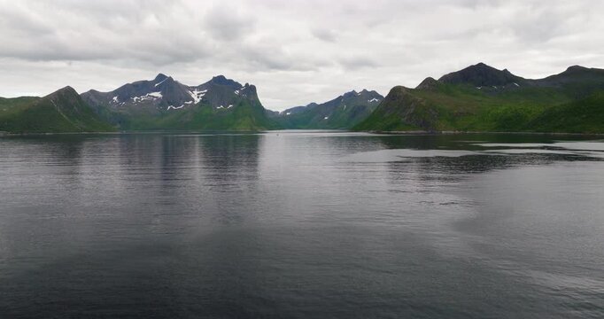 Aerial view of the dark waters of Oyfjord surrounded by rugged green mountains on the island of Senja in Northern Norway