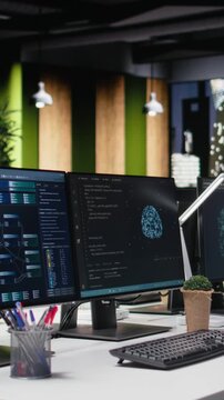 Vertical video showing computer in office automating app development tasks with AI scripts with empty workplace.