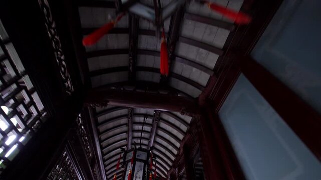 Red lanterns dangle from a traditional wooden ceiling in a Chinese architectural setting. Ideal for cultural documentaries or architectural studies.
