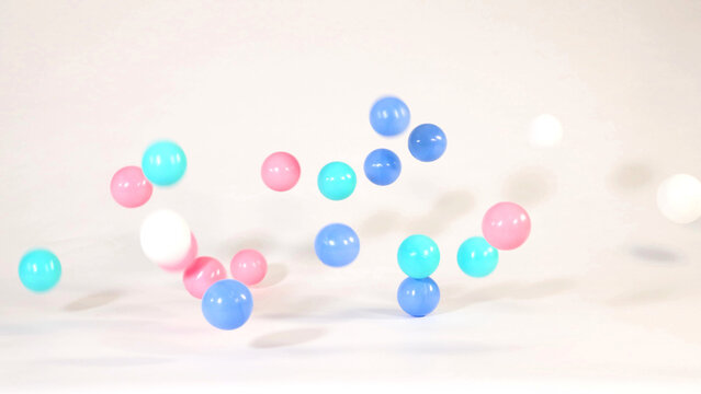 Colorful Pink Blue and Turquoise Plastic Balls Bouncing on White Surface