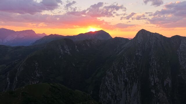 Drone shot moving left to right with aerial view above rocky mountain tops in Europe at sunset. Footage filmed in Pico de Europa mountains of northern, Spain with beautiful evening sky.