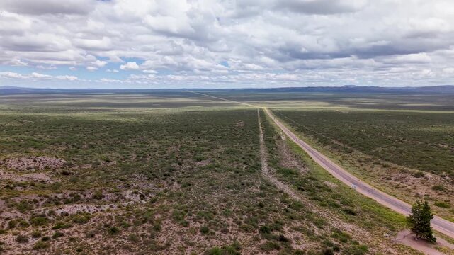 Ruta atravesando paisaje &aacute;rido con vegetaci&oacute;n nativa, autos circulando y nubes en un d&iacute;a soleado