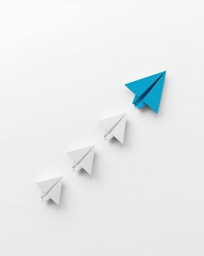 One blue paper airplane leading a group of white paper airplanes flying upwards representing leadership and success
