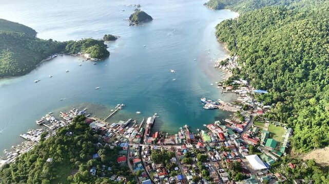 Aerial drone view of Liminangcong Port, revealing stilt houses and coastal housing along a tropical seascape, Philippines