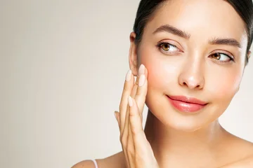 Skin care. Woman with beauty face touching healthy facial skin portrait. Beautiful girl model with natural makeup touching glowing hydrated skin on white background closeup © Oleg Gekman