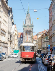 Fototapeta premium Explore the charm of Prague on a sunny April day with tram 9 passing historic architecture