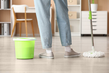 Fototapeta premium Person cleaning home floor with mop and bucket, housekeeping and domestic chores, residential maintenance and hygiene
