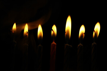 Obraz premium Row of Illuminated Candle Flames Against Dark Background - Warm, Atmospheric Lighting for Celebrations