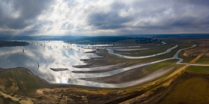 Aerial panorama view of foggy morning light over creeks flowing into a reservoir full of dead trees