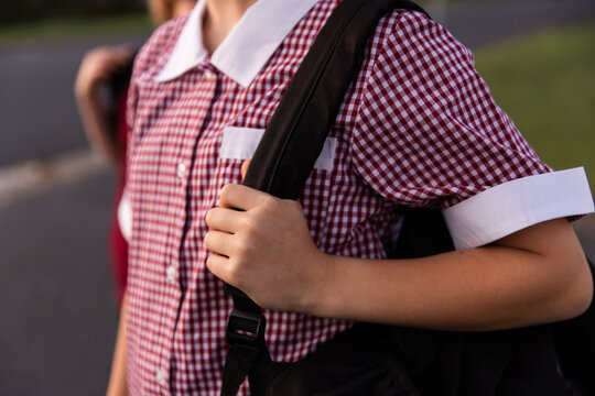 close up of a girl wearing a gingham school dress with a bag over one shoulder