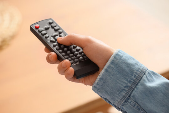 Hand holding black remote control for home entertainment system, leisure and technology