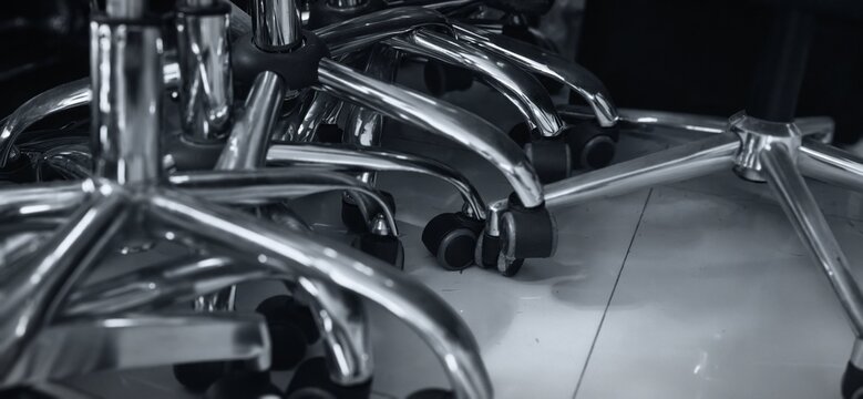 Abstract industrial background of stacked office chair chrome bases and caster wheels.
