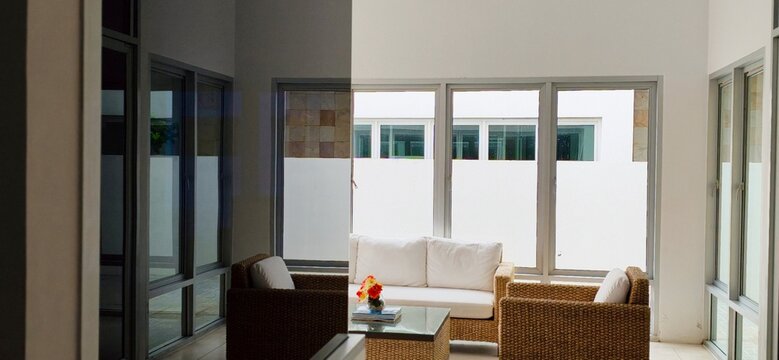 Modern luxury living room interior with wicker sofa furniture and big glass windows.