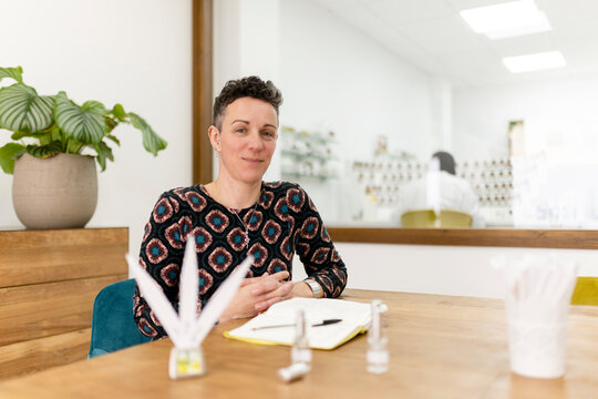 Portrait of a female perfumer smiling at her workshop desk