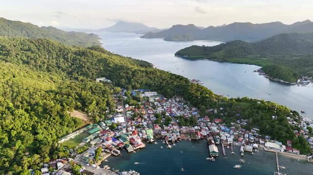 Aerial drone view of Liminangcong Port, revealing stilt houses and coastal housing along a tropical seascape, Philippines
