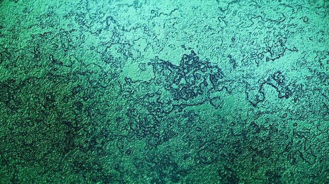 Slowly moving emerald green metallic fluid with a rough organic texture and glossy reflections for background video.