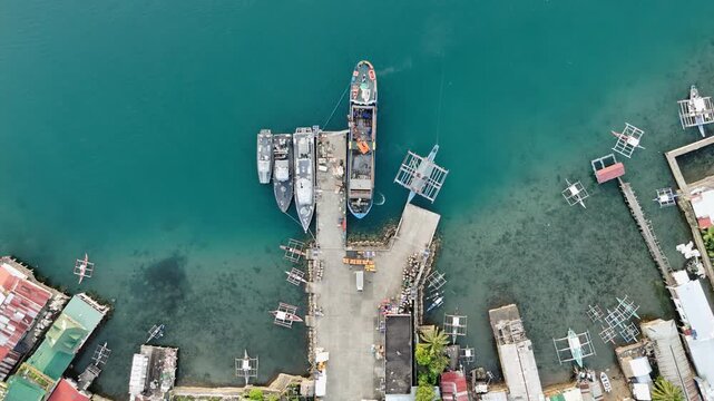 Aerial drone view of Liminangcong Port, revealing stilt houses and coastal housing along a tropical seascape, Philippines