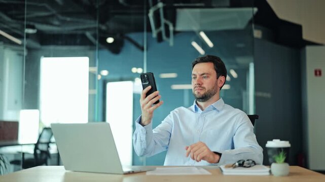 Corporate manager or IT specialist looking at phone, searching for stable mobile internet, coverage or wireless connection. Disappointed employee holding device high up due to bad connection at desk