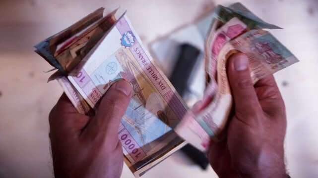 Global currency banknotes being handled by criminal hands on a desk. Moody high-contrast cinematic style for dark web and underground economy concepts in POV.