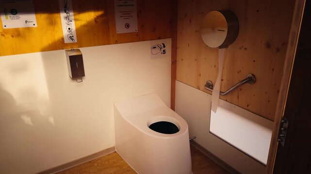 Clean and modern composting toilet installation inside a light wood cabin. Wide-angle view with warm cinematic tones highlighting eco-friendly sanitation solutions.