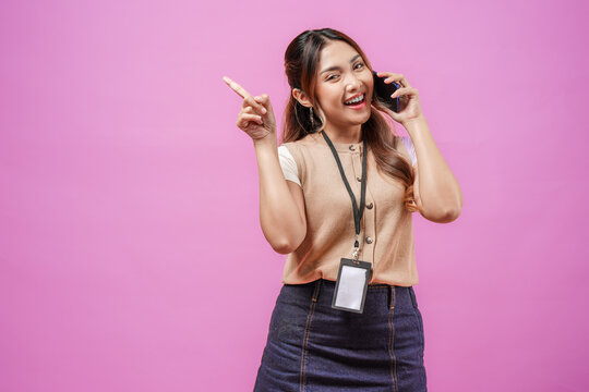 Cheerful young Asian woman is having a call while pointing to the copy space upwards.