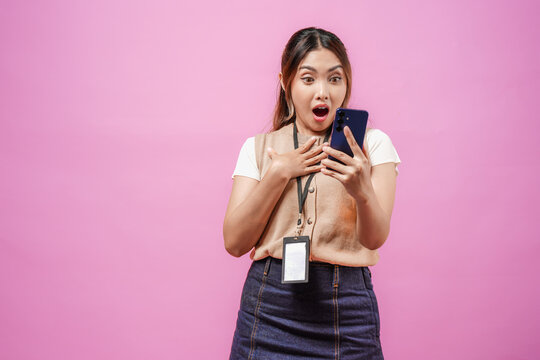 Shocked young Asian woman is holding a smartphone with a surprised expression on her face.