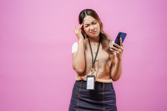 Stressful young Asian woman wearing office attire is holding smartphone and looking confused.
