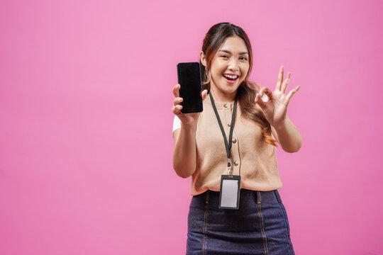 Attractive young Asian woman gives okay finger gesture while showing copy space on her phone.