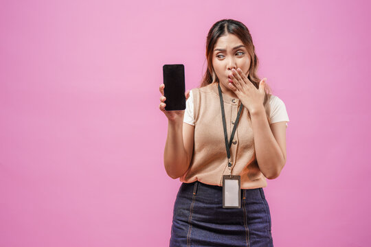 Surprised young Asian woman is holding and showing the copy space on phone screen.