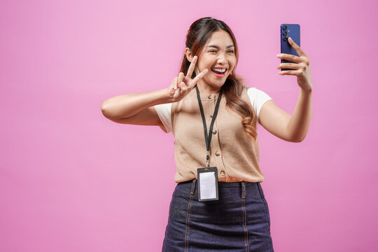 Cute young Asian woman in taking a selfie with her cell phone with peace finger gesture.