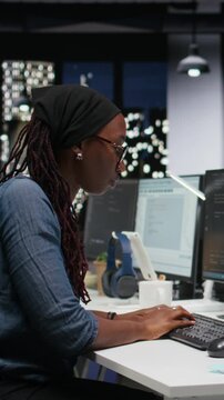 Vertical screen view of panicked female engineer in office requests help from colleagues to block hacker intrusion with teamwork context.