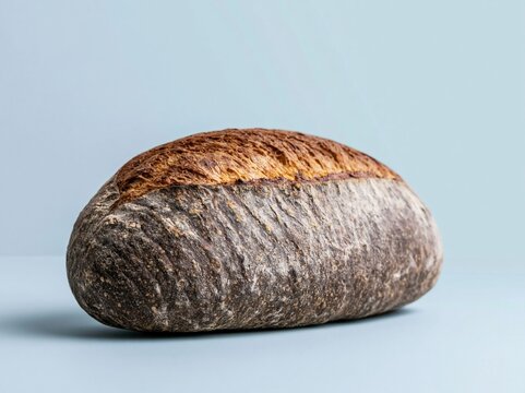 Fresh artisan sourdough bread loaf with a dark scored crust on a blue background for bakery menu design, organic food advertising and culinary product packaging