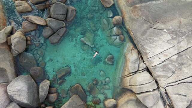 Aerial Top Down View of Woman Floating in Natural Granite Rock Pool Ko Samui Thailand
