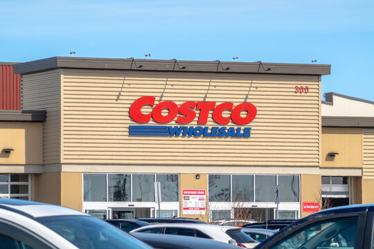 Calgary, Alberta, Canada. June 10, 2026. Daytime eye-level shot of the front entrance sign and exterior of a busy Costco Wholesale store.