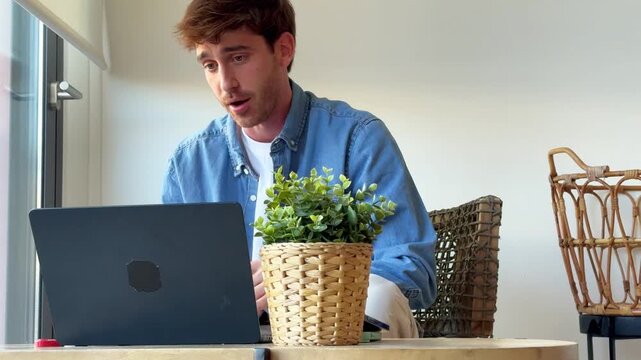 young man working on laptop in home office set up with concentration and focused on online job