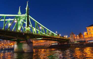 Naklejka premium A stunning night view of Budapest's famous Liberty Bridge crossing the Danube River showcasing dramatic architecture and illuminated city lights travel destination photo