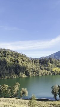 Beautiful scenic view of Ranu Kumbolo lake with green hills and clear blue sky in Mount Semeru Indonesia