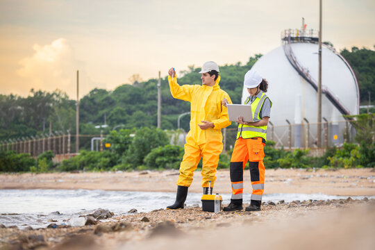 Professional scientists team performing environmental monitoring and water pollution testing outdoors, Environmental engineers collecting analyzing water quality samples at coastal industrial site