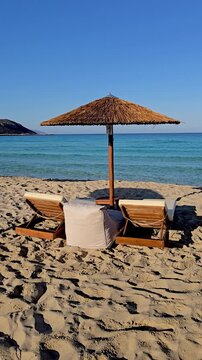Experience the serene atmosphere of Simos Beach, Elafonisos Island, Greece, where golden sands meet crystal-clear waters under a clear blue sky. Perfect for relaxation and sunbathing.
