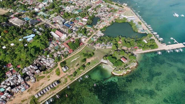 High-altitude pull-away riser drone shot showcasing Fort Santa Isabel and the coastal town of Taytay, Palawan. The coral-stone Spanish fort stands out amid the tropical settlement