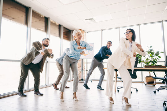 Business professionals smiling and dancing in the office for a teambuilding exercise