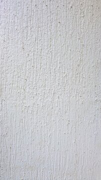 A close-up of a textured white wall with vertical brush strokes and subtle imperfections, ideal for background or design purposes.