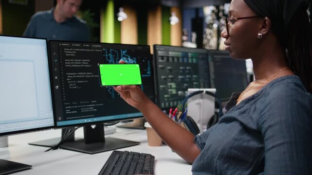 Green screen phone used by woman in workplace doing tech quality assurance with coding and programming workflow.