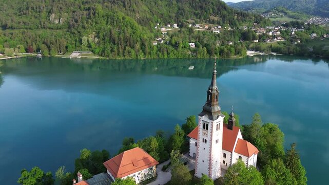 Aerial view of Bled Island with the Assumption of Mary Church on Lake Bled, Slovenia. Beautiful cinematic footage of the iconic island surrounded by turquoise blue water and Alps mountains