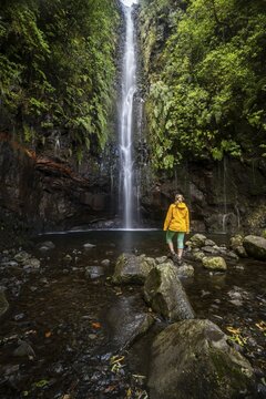 Young woman standing by the river and waterfall Cascata das 25 Fontes, long exposure, Rabacal, Paul da Serra, Madeira, Portugal